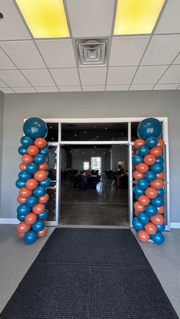 Teal and terracotta balloon columns framing event entrance