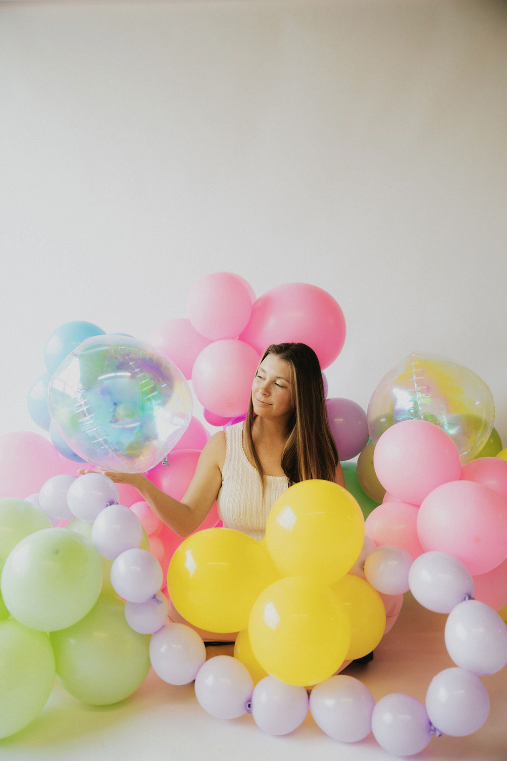 Jenni surrounded by a colorful balloon arrangement